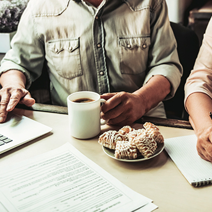 Couple sitting in kitchen eating breakfast working on a laptop