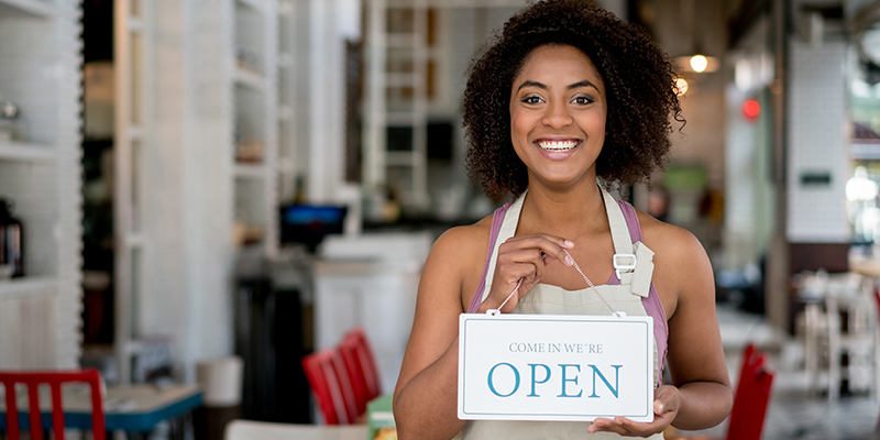 Woman in a cafe holding an open sign